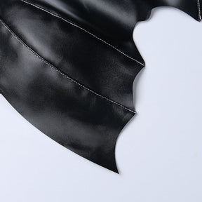 Close view of the pointed lower edge of the black bat wing bralette, with stitched curved sections across the glossy surface.