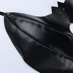 Detail of a glossy black bralette wing laid on white, with curved rows of stitching leading toward the pointed tip.