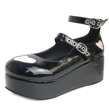 Glossy black platform Mary Jane with pink heart appliques and two grommeted buckle straps, showing the reflective finish from the side.