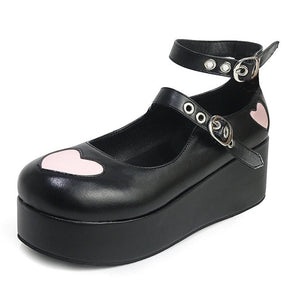 Matte black platform Mary Jane with large pink hearts on the toe and outer heel, plus two buckle-fastened straps.