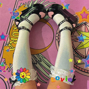 Black big-heart Mary Janes worn with pale green socks, both feet angled upward over a brightly colored illustrated background.