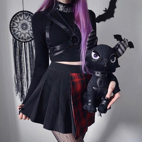 Black Blessed embroidered turtleneck crop top styled with a separate harness and split plaid skirt.