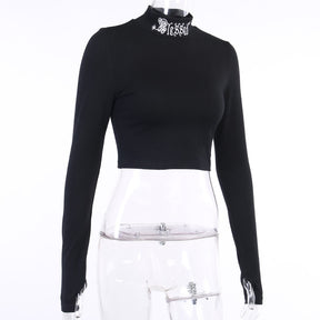 Black Blessed embroidered turtleneck crop top displayed at an angle on a clear mannequin.