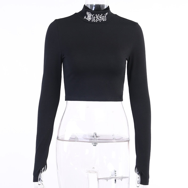 Black Blessed embroidered turtleneck crop top displayed from the front on a clear mannequin.