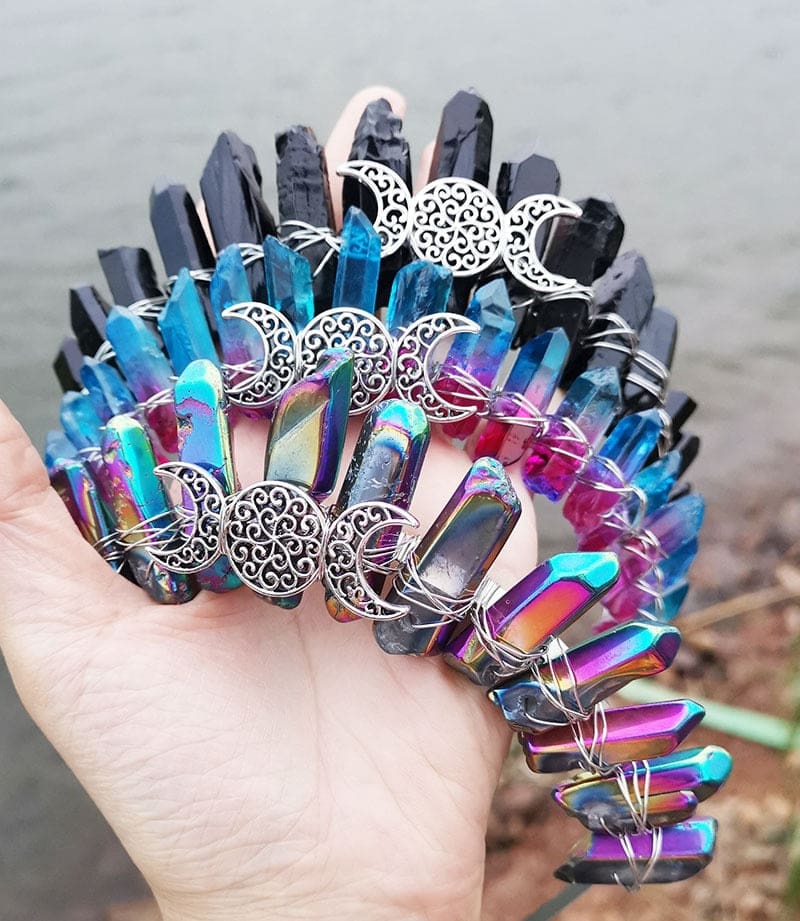 Black, blue-pink and metallic rainbow crowns shown as a trio, each with a silver-tone lunar centre beneath pointed crystals.