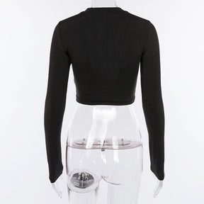 Rear view of the black long sleeve crop top on a clear mannequin, showing the plain covered back and cropped hem.