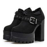 Pair of black faux-suede ankle booties with rounded toes, short lace-up fronts and wide eyelet buckle straps above tall platforms and block heels.