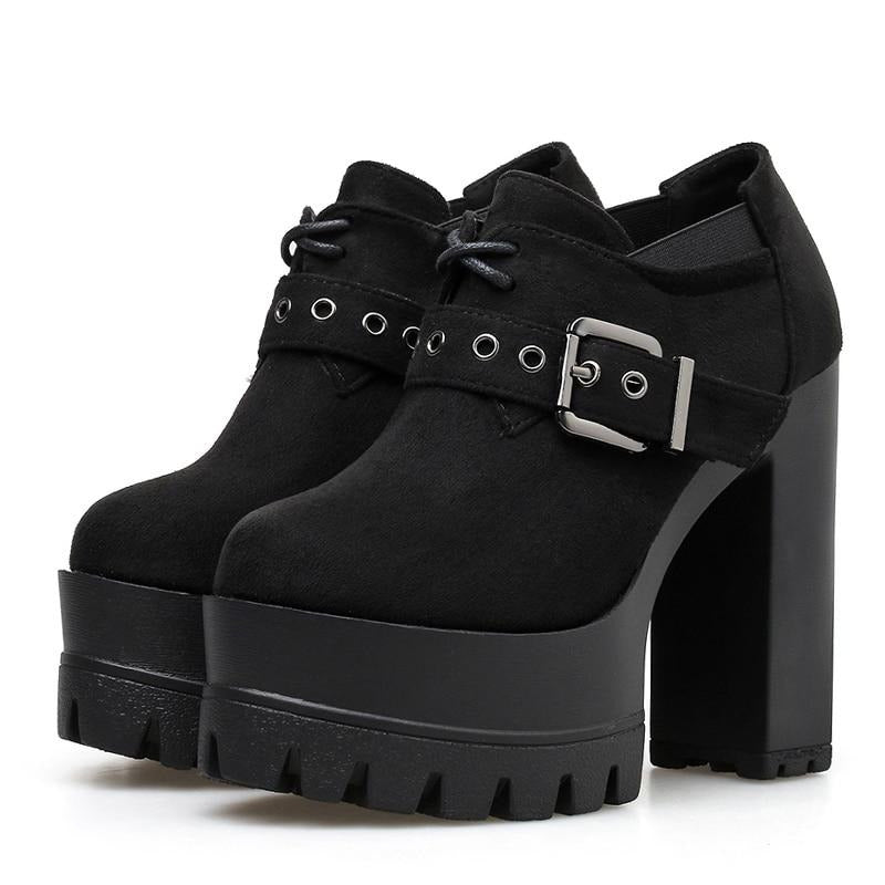 Pair of black faux-suede ankle booties with rounded toes, short lace-up fronts and wide eyelet buckle straps above tall platforms and block heels.