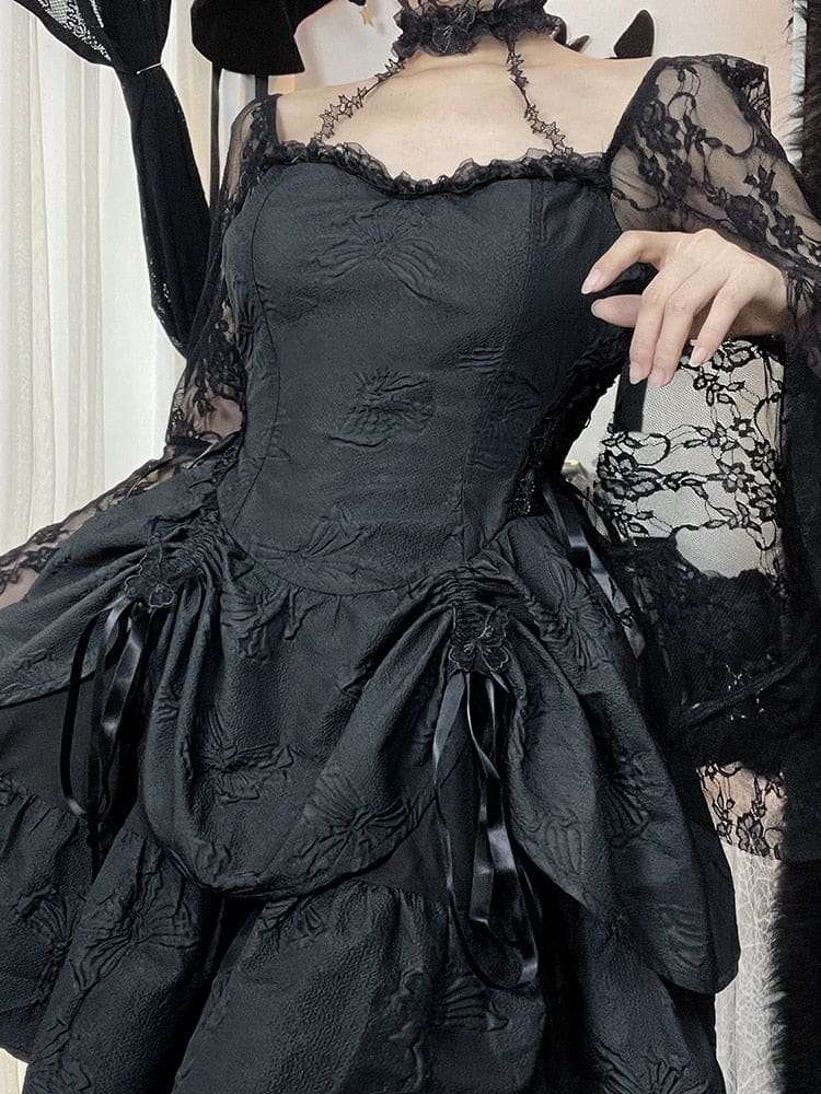 Angled front view of the black Dark Chapel dress with one hand raised near the neckline. The choker straps, lace sleeves and gathered skirt are visible.