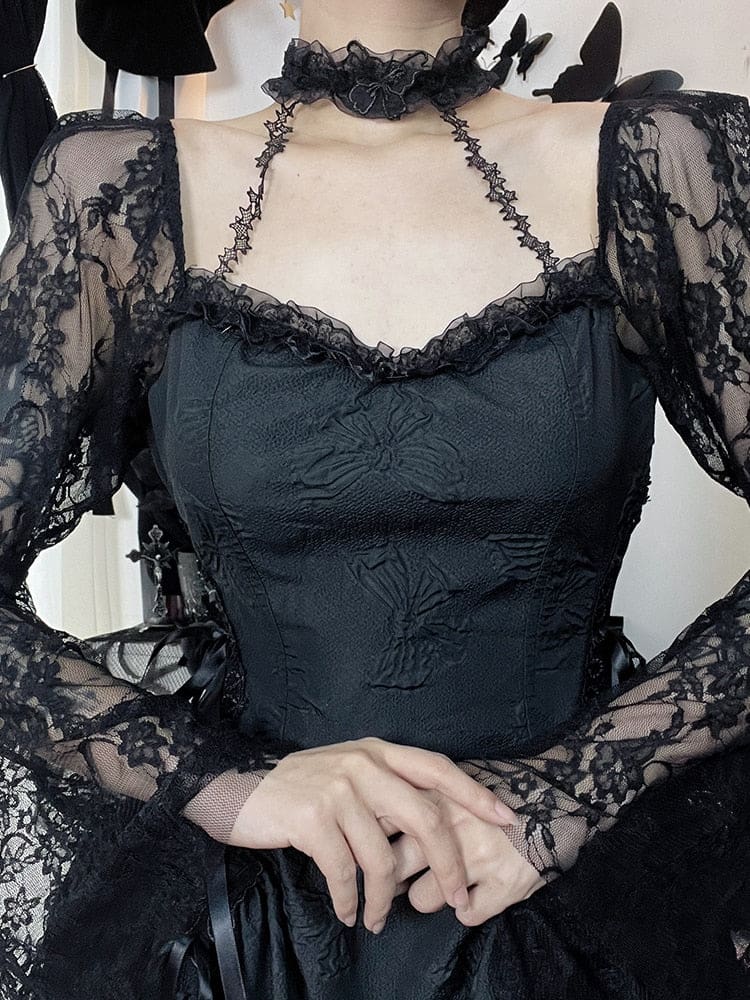Close front view of the black dress bodice, scalloped lace neckline and attached choker. The model holds both hands together, showing the floral lace sleeves and narrow connecting straps.