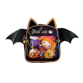 Cat-ear bat-wing backpack isolated against white, showing golden-orange edging, Bat cat lettering and a clear pocket filled with Halloween-themed display plushies.