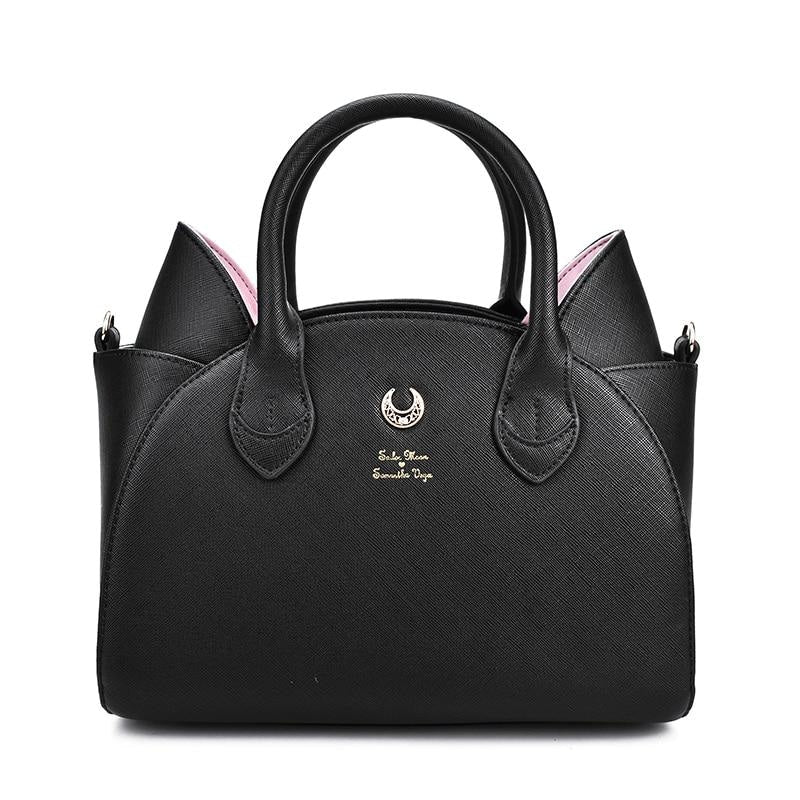 Straight-on view of the black crescent-moon handbag, highlighting the rounded body, two arched handles and pointed cat ears against white.