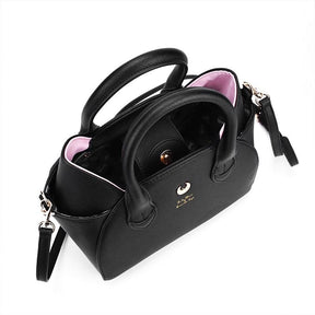 Top view into the open black cat-ear handbag, revealing its dark patterned lining beneath the twin handles and gold-tone hardware.