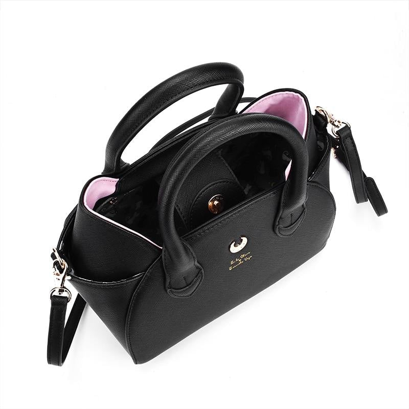 Top view into the open black cat-ear handbag, revealing its dark patterned lining beneath the twin handles and gold-tone hardware.