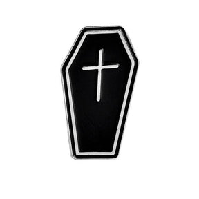 Black coffin-shaped enamel pin with a silver-tone border and a small cross on its front.