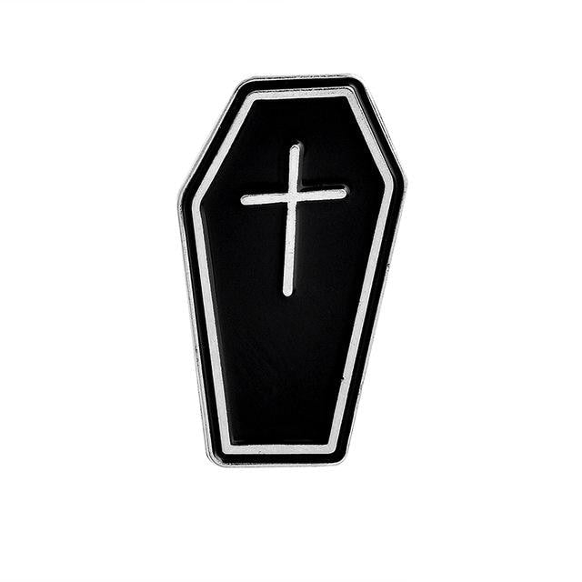 Black coffin-shaped enamel pin with a silver-tone border and a small cross on its front.