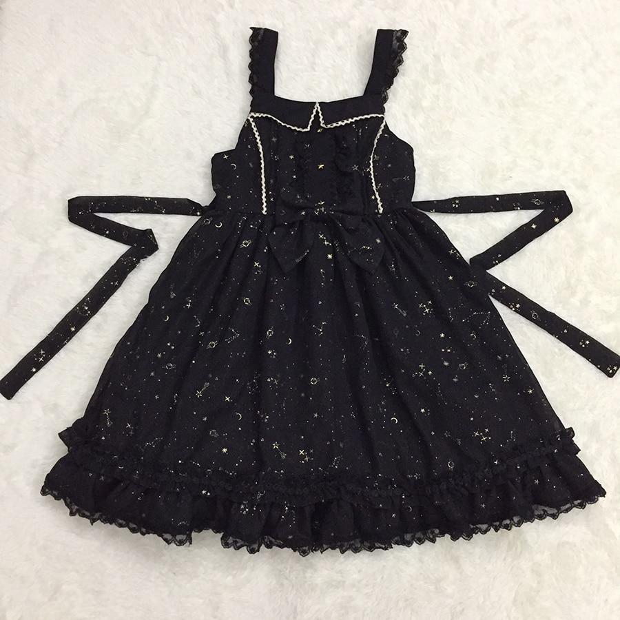 Black star-print pinafore dress laid flat with its long waist ties extended to either side.