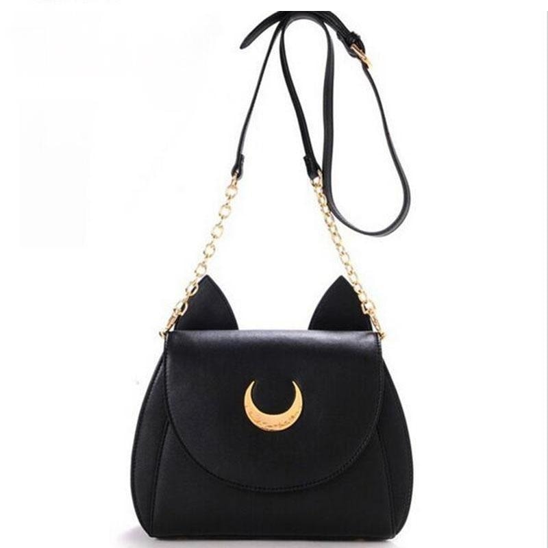 Black crescent-moon cat-ear bag hanging from its extended strap, showing the buckle adjustment and gold-tone chain sections.