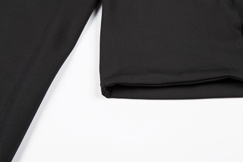 Close view of the black crop top fabric and neatly folded lower hem beside a sleeve.