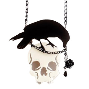 Front view of the suspended skull-and-crow necklace, with the black bird stretching across the skull and the faceted drop hanging at one side.