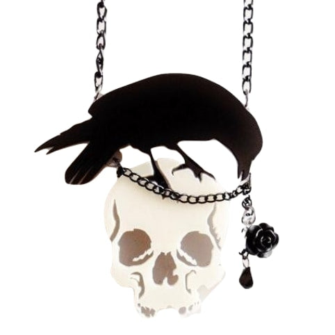 Front view of the suspended skull-and-crow necklace, with the black bird stretching across the skull and the faceted drop hanging at one side.