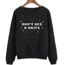 Black witchy crewneck sweatshirt hanging against a pale background, with pale DON’T HEX & DRIVE lettering and scattered moons and stars across the chest.