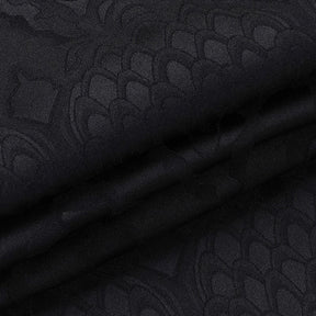Folded black dragon-pattern fabric from the cheongsam dress, showing the contrast between matte and softly reflective areas of the motif.