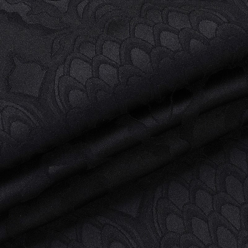 Folded black dragon-pattern fabric from the cheongsam dress, showing the contrast between matte and softly reflective areas of the motif.