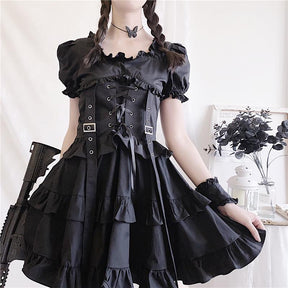 Front view of the black puff-sleeve dress showing the corset lacing, two buckles and long ribbons above a tiered skirt.