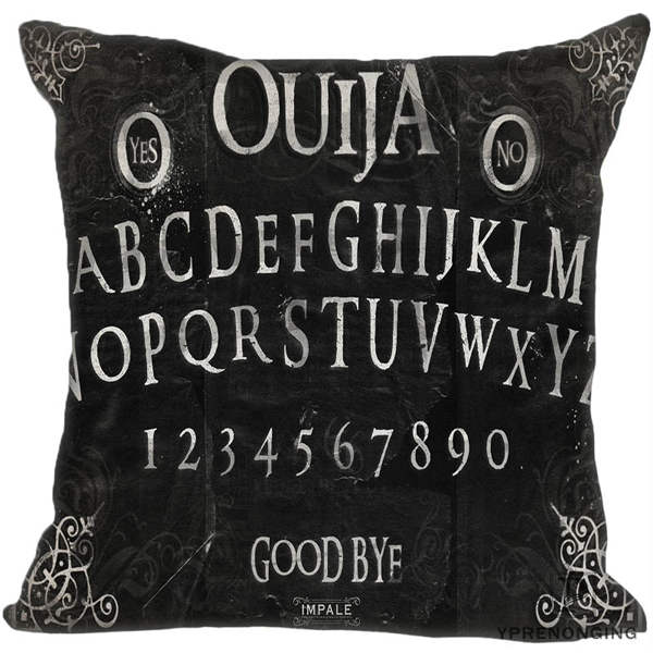 Black square Ouija pillow cover with pale serif alphabet rows, numbers, Yes and No medallions and fine scrollwork around the corners.