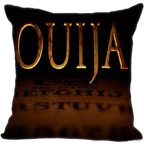 Black square pillow cover with oversized golden Ouija lettering above a shadowy brown spirit board.