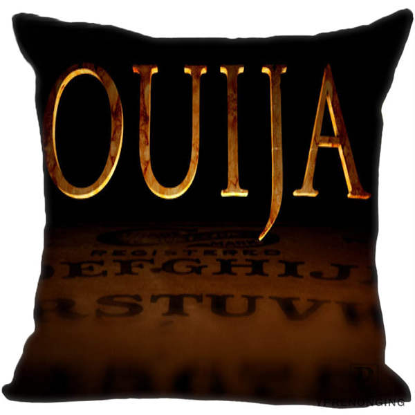 Black square pillow cover with oversized golden Ouija lettering above a shadowy brown spirit board.