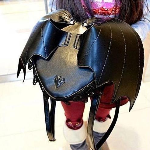 Black bat wing backpack with curved wing stitching, lace trim, a zip closure, and buckle shoulder straps.