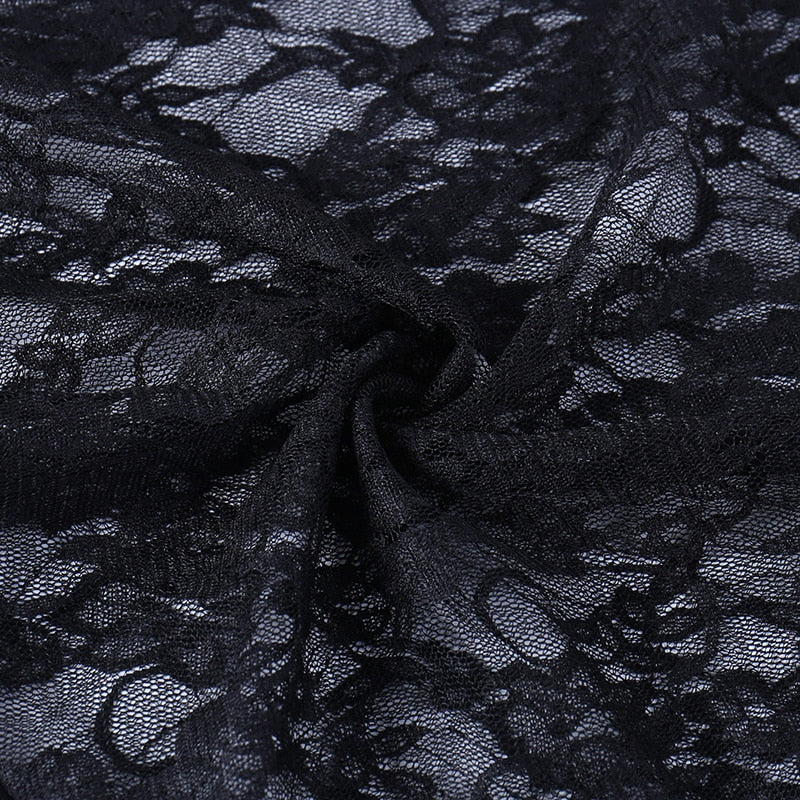 Close-up of gathered black floral lace, showing the sheer mesh ground and raised flower pattern of the overlay.