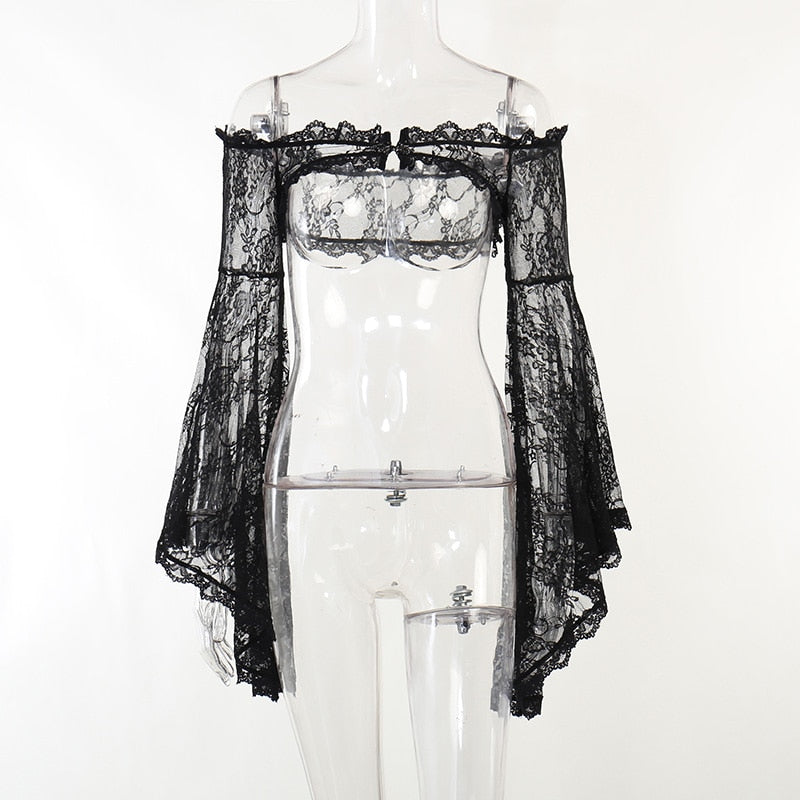 Front view of the black lace overlay on a clear mannequin, showing the open front beneath its clasp and asymmetrical bell-sleeve edges.