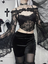 Front view of the black off-shoulder lace overlay over a separate pointed-hem camisole. The long sleeves fall beside velvet shorts and sheer tights.
