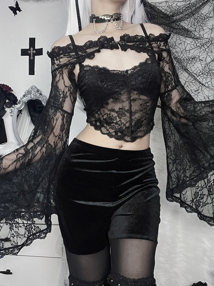 Front view of the black off-shoulder lace overlay over a separate pointed-hem camisole. The long sleeves fall beside velvet shorts and sheer tights.