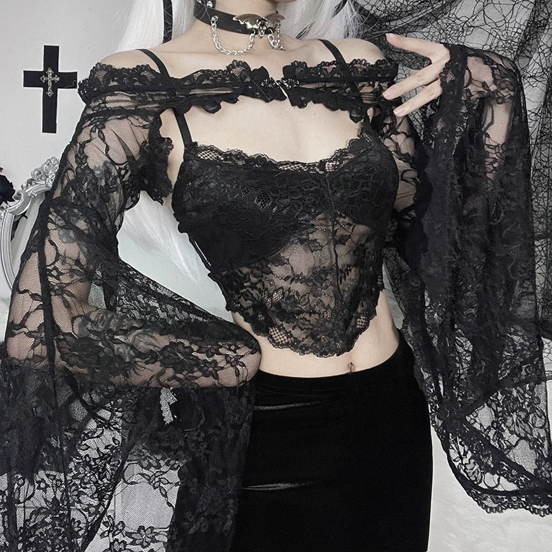 Cropped outfit view of the off-shoulder lace overlay, with one hand at the shoulder and the opposite sleeve draped across the waist.