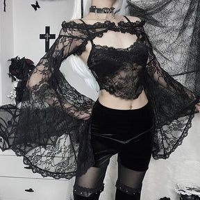 Wider view of the black lace shoulder overlay worn with velvet shorts and sheer tights, with both bell sleeves held away from the body.