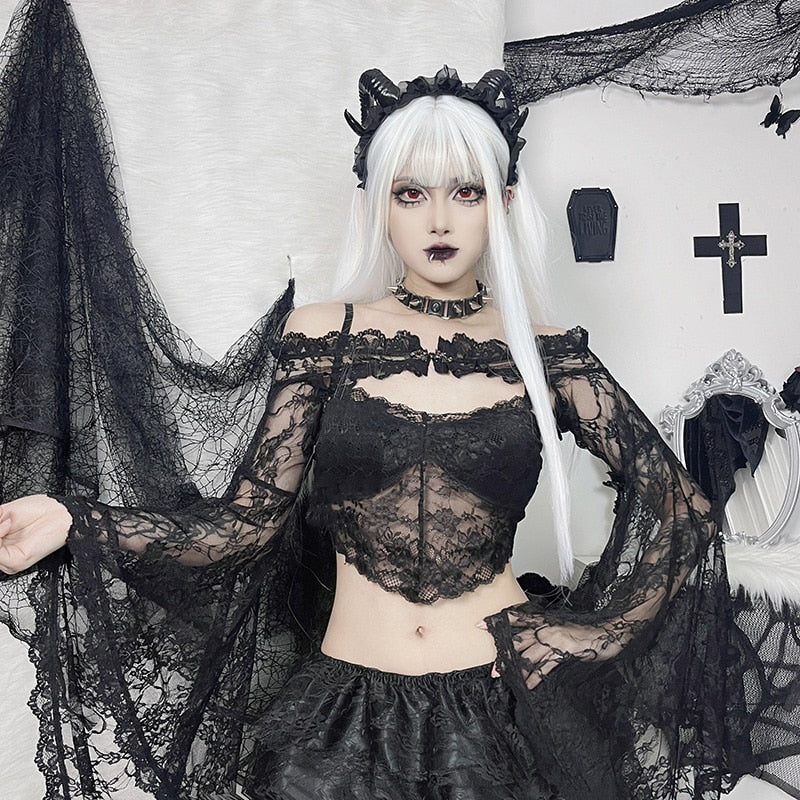 Model wearing the black lace shoulder overlay and a separate lace cami, with long white hair, a black headpiece and both sleeves spread.