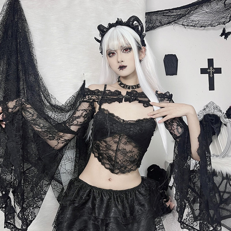Black off-shoulder lace overlay styled with a black skirt and separate cami, with one arm raised to show the cascading sleeve.