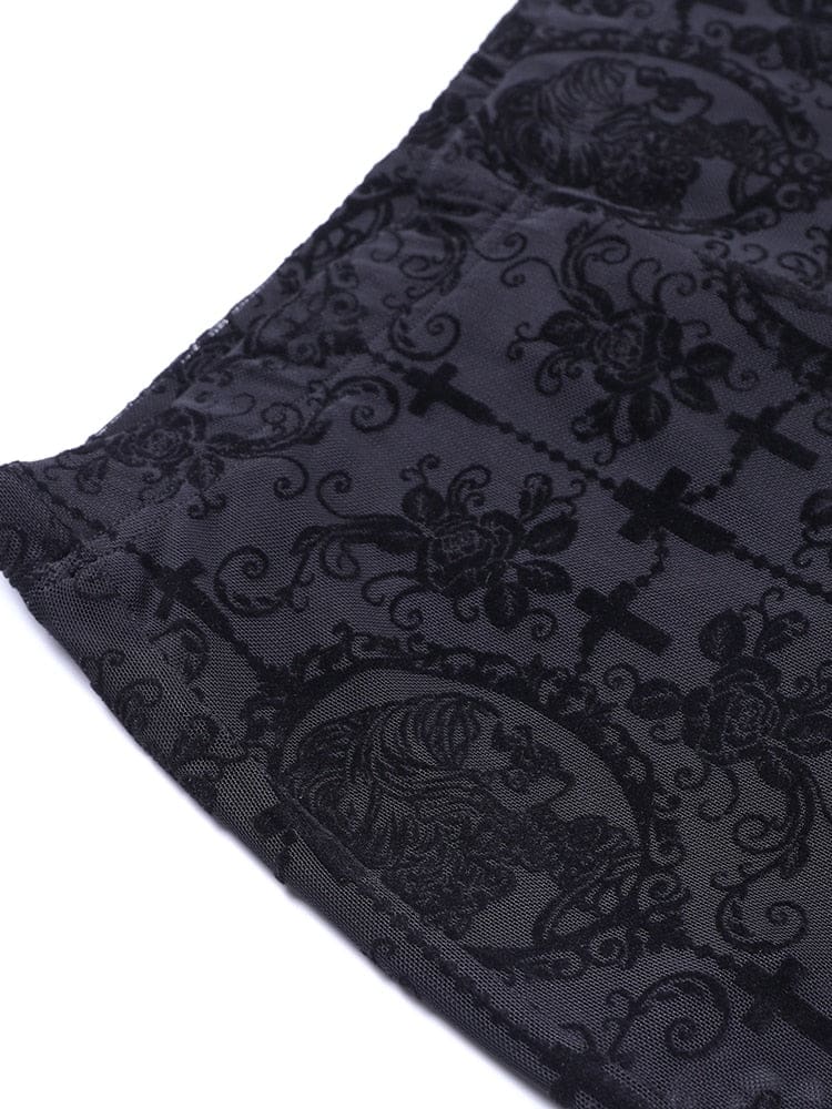 Detail of a black flared trouser hem laid on white, showing skeletal cameo shapes and scrolling decoration in the sheer mesh.