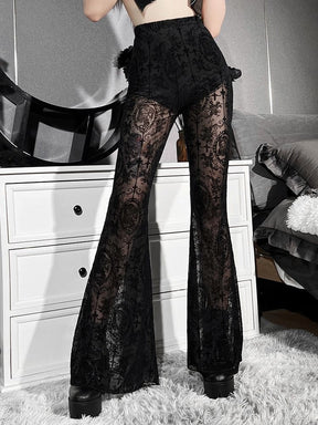 Three-quarter view of the black high-waisted bell bottom pants. The long flared legs show an ornate dark pattern against translucent mesh.