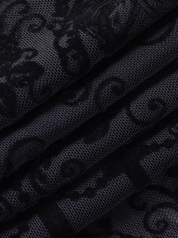 Black ornate patterned mesh gathered into soft folds, showing the contrast between dense scroll shapes and the sheer ground of the bell bottoms.