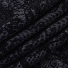 Close-up of the black bell bottom fabric folded against a pale surface, with fine mesh and dark raised-looking ornamental motifs.