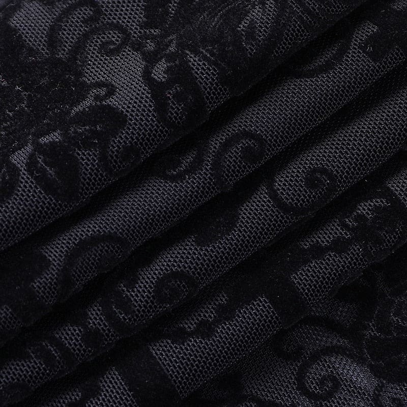 Close-up of the black bell bottom fabric folded against a pale surface, with fine mesh and dark raised-looking ornamental motifs.