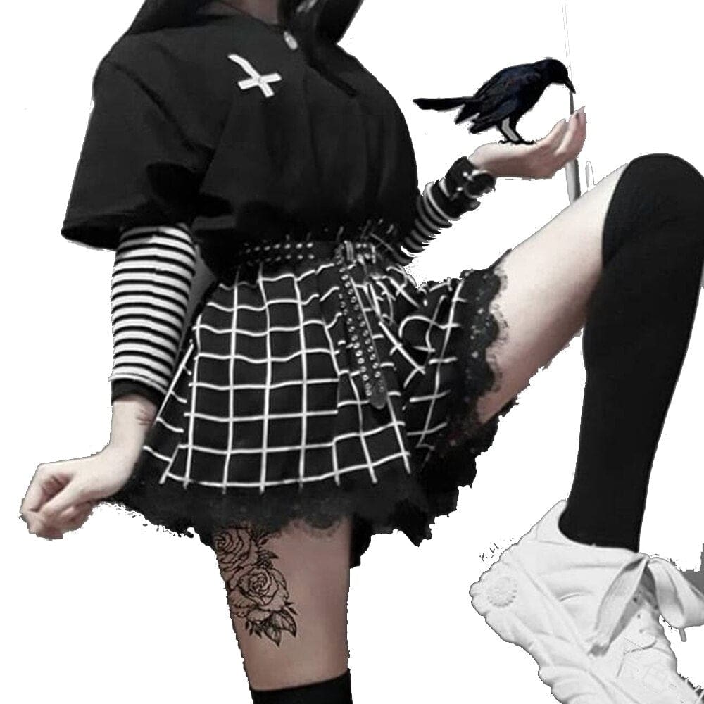 The black grid-print skort shown in a raised-leg pose against white, with a striped sleeve, studded belt and thigh-high sock framing its flared lace-trimmed shape.