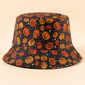 Black bucket hat with orange pumpkin faces photographed against a warm pale background. Rows of stitching follow the curved brim.