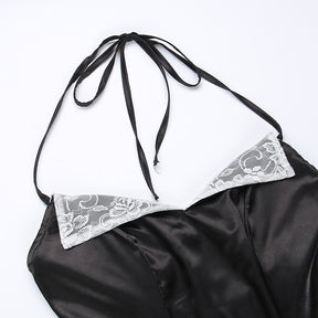 Top of the black dress laid on white, showing the long halter ties and pointed white lace lapels.