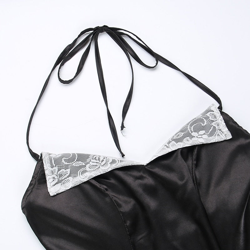 Top of the black dress laid on white, showing the long halter ties and pointed white lace lapels.